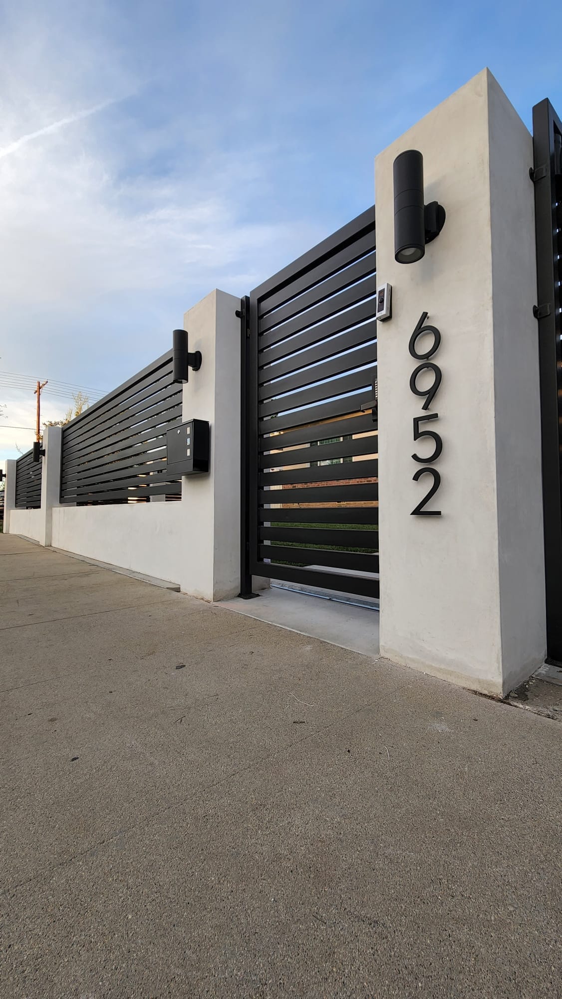 SGD Services Review v1 4 Lake Balboa. Complete project — columns, lighting, intercom system, driveway gate with vertical slats, pedestrian gate, and horizontal-design metal fence.