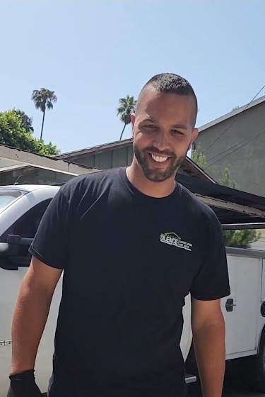 Tal Karta of Silence Garage Door & Gates on site in a Silence shirt and work gloves, service truck behind him