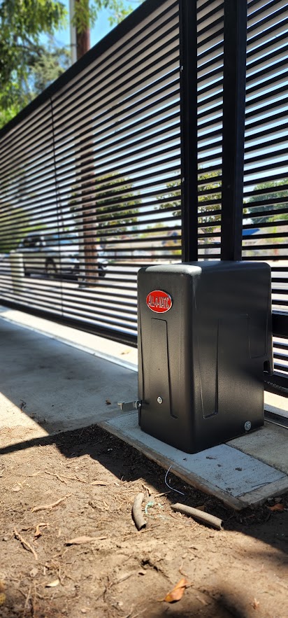 Gate Repair in Sherman Oaks, CA 16 All-O-Matic slide gate operator in a black housing standing beside a horizontal slat sliding gate