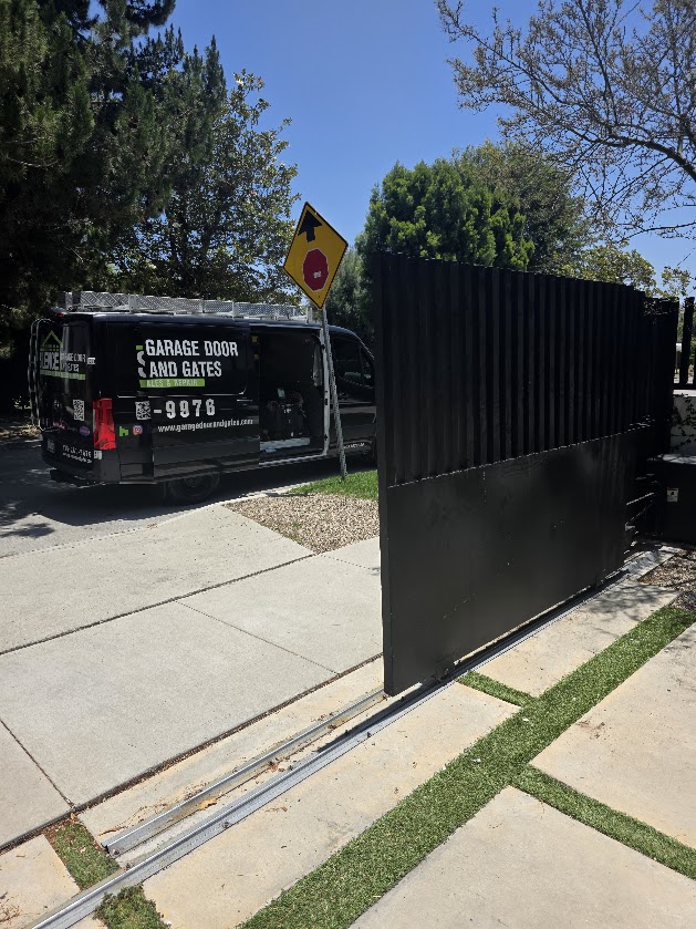 Gate Repair in Sherman Oaks, CA 5 The repaired dark slatted sliding gate closed and running on its track, with the service van parked at the kerb
