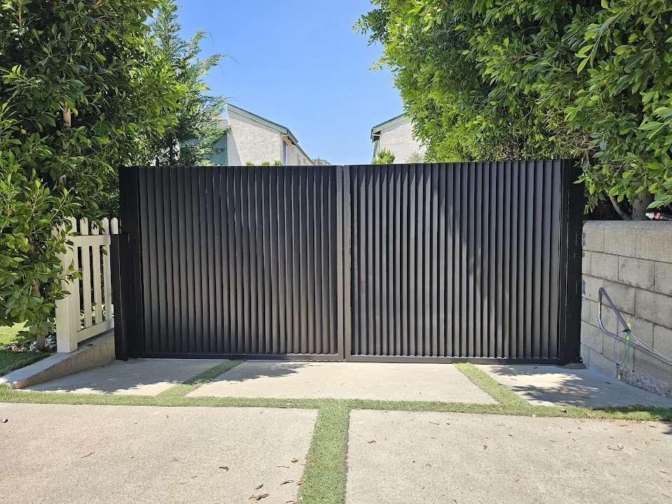 Gate Repair in Sherman Oaks, CA 14 Dark double swing driveway gate with vertical corrugated steel panels, closed across a concrete driveway