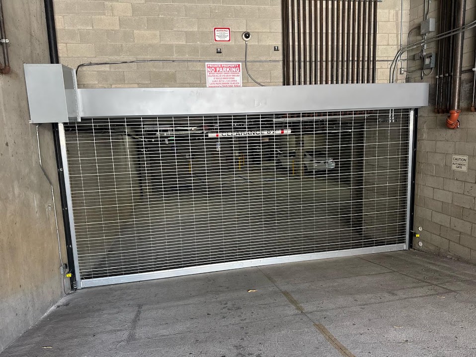 Gate Repair in Sherman Oaks, CA 18 Galvanised steel mesh rolling security grille partly closed across an underground parking garage entrance, with its coil housing above