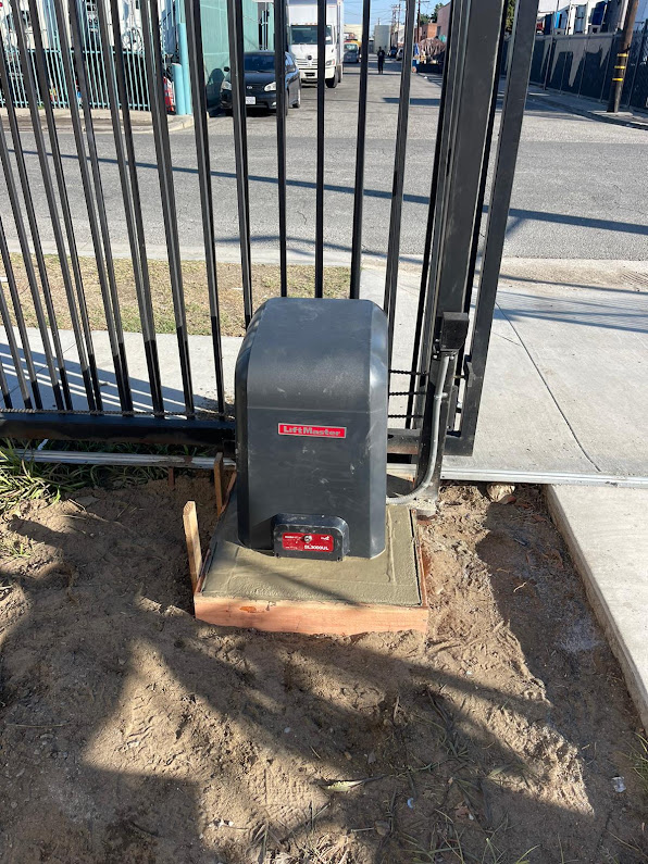 Gate Repair in Sherman Oaks, CA 15 LiftMaster SL3000UL slide gate operator with its cover on, mounted on a concrete pad beside a wrought iron gate